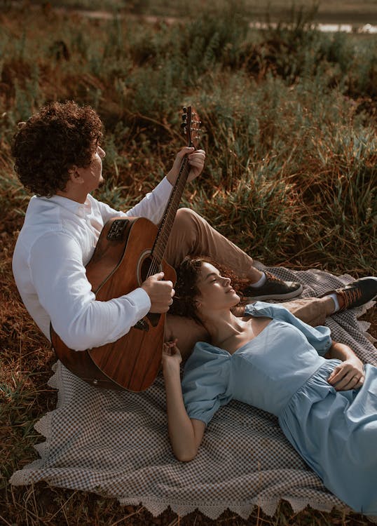 Une femme allongée et un homme jouant à la guitare