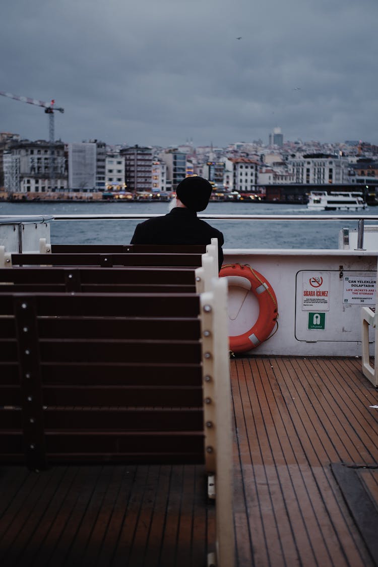 Man Sitting On Bench On Ferry Deck