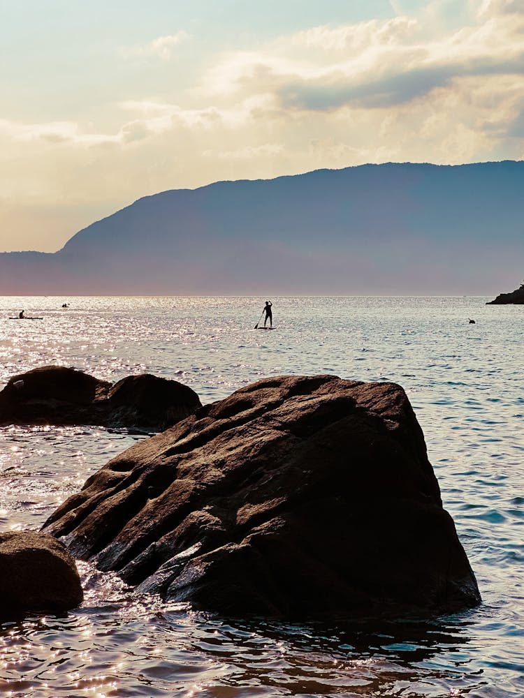 Man Surfing On Board In Sea On Sunset