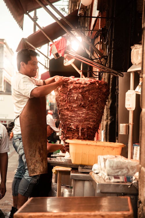 Man in an Apron Putting Meat on a Pole 