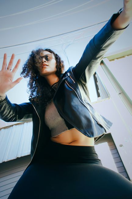 Low angle shot of a woman in a leather jacket and sunglasses, exuding style and confidence.