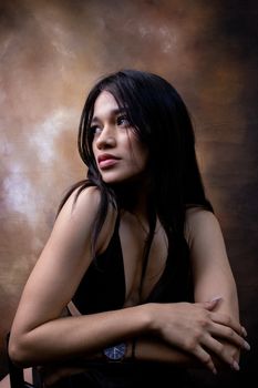 A striking studio portrait of a young woman with long brunette hair, showcasing elegance and beauty.