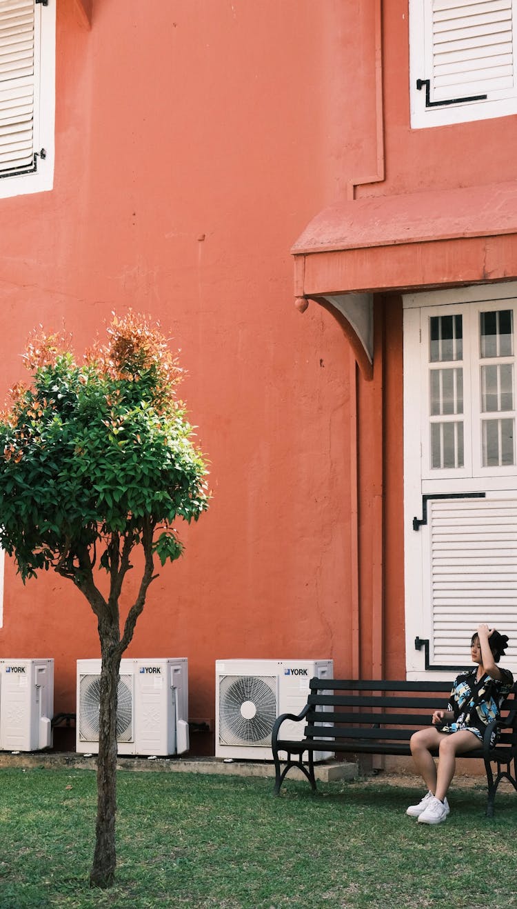 Woman Sitting On Wooden Bench In Yard