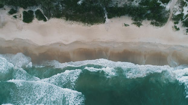 Stunning aerial shot of Florianópolis beach showing turquoise waves crashing on the sandy shore.