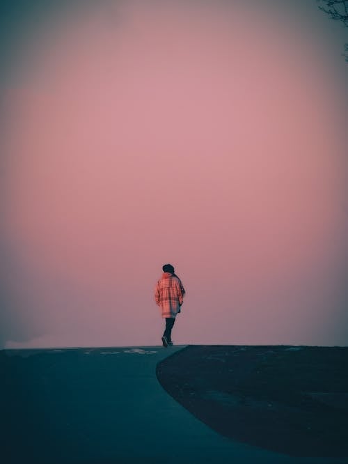 Silhouette of a Person Walking on a Road at Dusk 