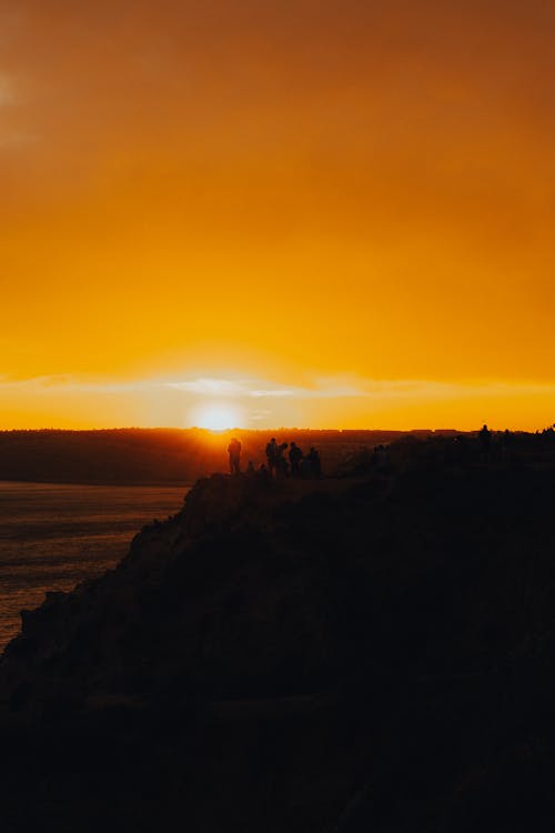 People on Cliff in Nature on Sunset