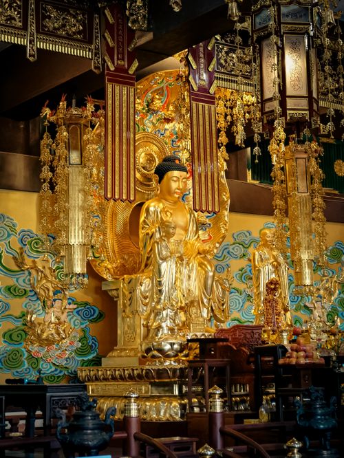 Free A magnificent golden Buddha statue adorned with intricate ornaments inside a temple setting. Stock Photo