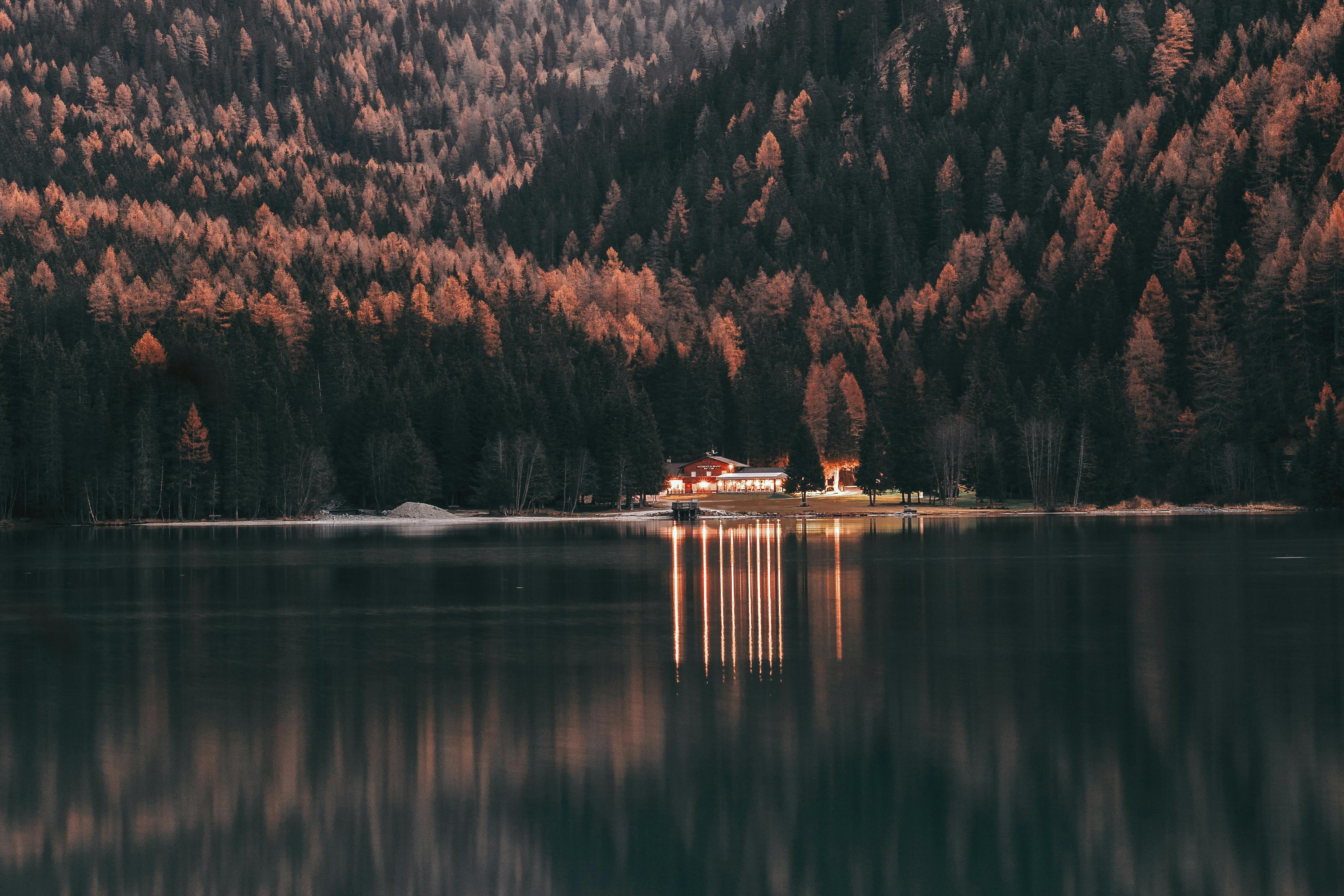 landscape photography of house near woods and calm body of water
