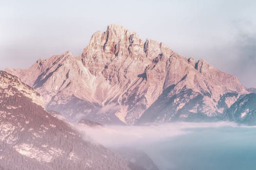 Stunning view of a sunlit mountain peak rising above the morning fog, creating a serene and majestic landscape.