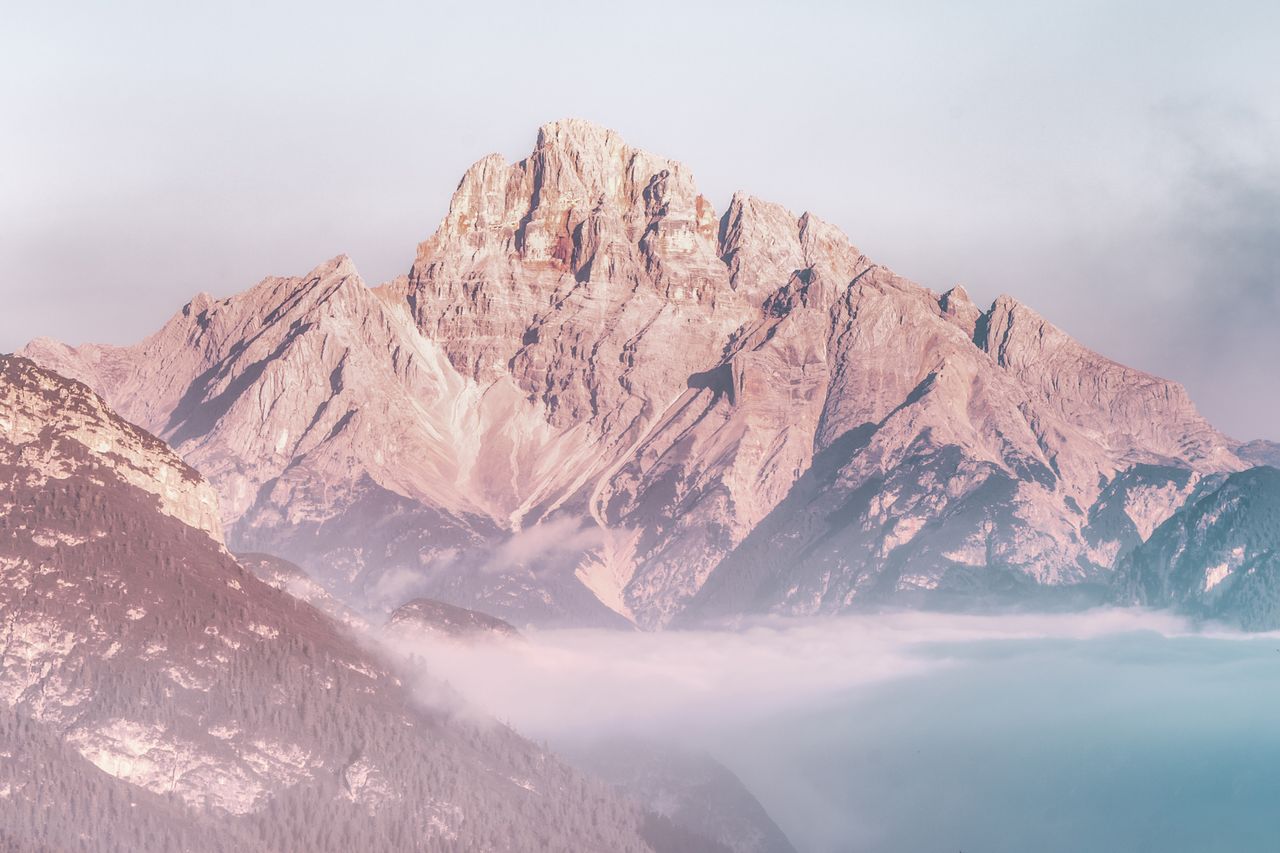 stunning view of a sunlit mountain peak rising above the morning fog c