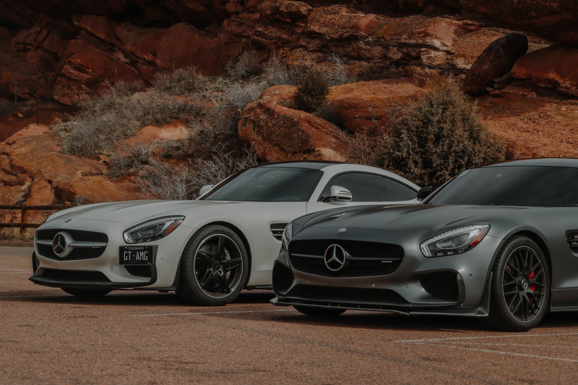 Two Mercedes-AMG GT sports cars at Red Rocks, Colorado, showcasing sleek design in a stunning outdoor setting.