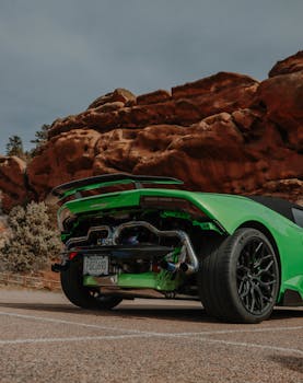 Luxury sports car with vivid green color parked against dramatic rocky landscape, showcasing performance and design.