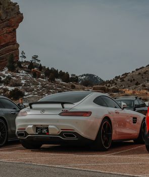 White Mercedes-Benz AMG GT parked in a snowy mountain parking lot.