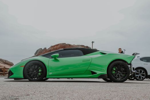 A striking green Lamborghini Huracan parked at Red Rocks under a cloudy sky.
