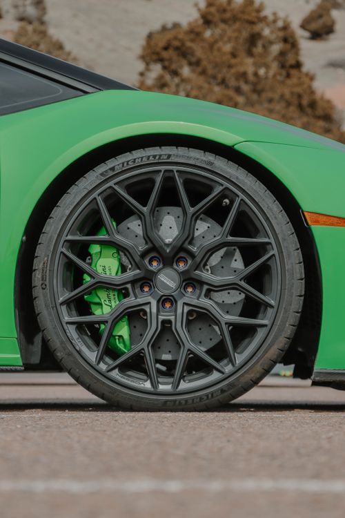 Free Detailed close-up of a black car wheel and rim with green calipers on a sports car. Stock Photo