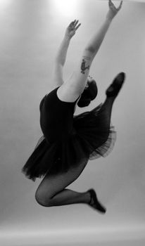 Elegant black and white photo of a ballerina mid-jump, capturing the grace and power of dance.