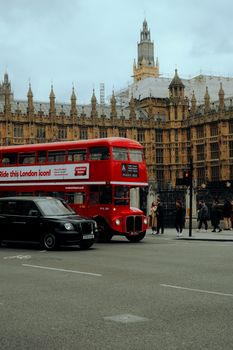 Iconic red London double-decker bus passing by the historic Big Ben.