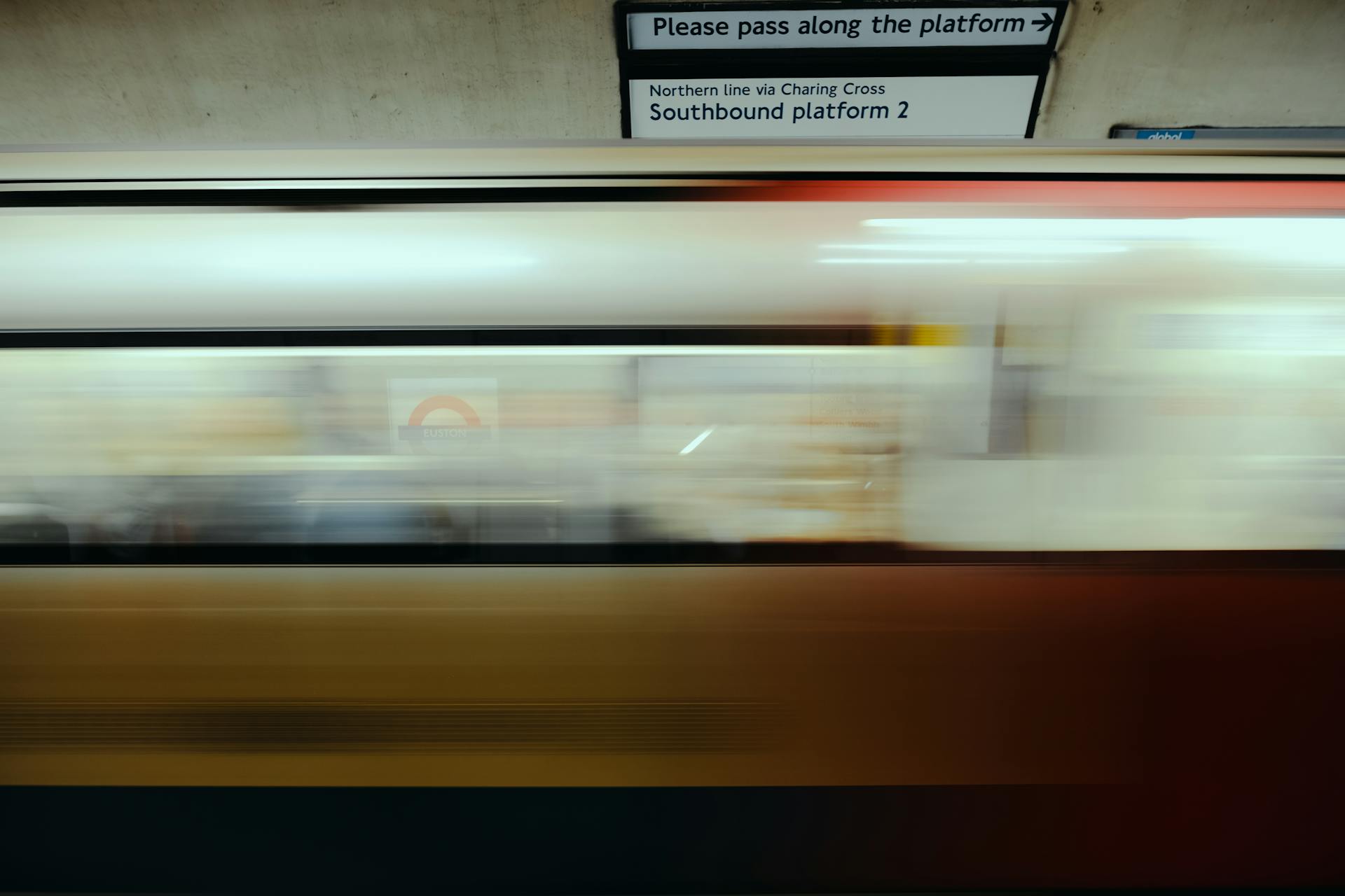 A dynamic shot of a London Underground train speeding past a station platform, capturing urban transit energy.