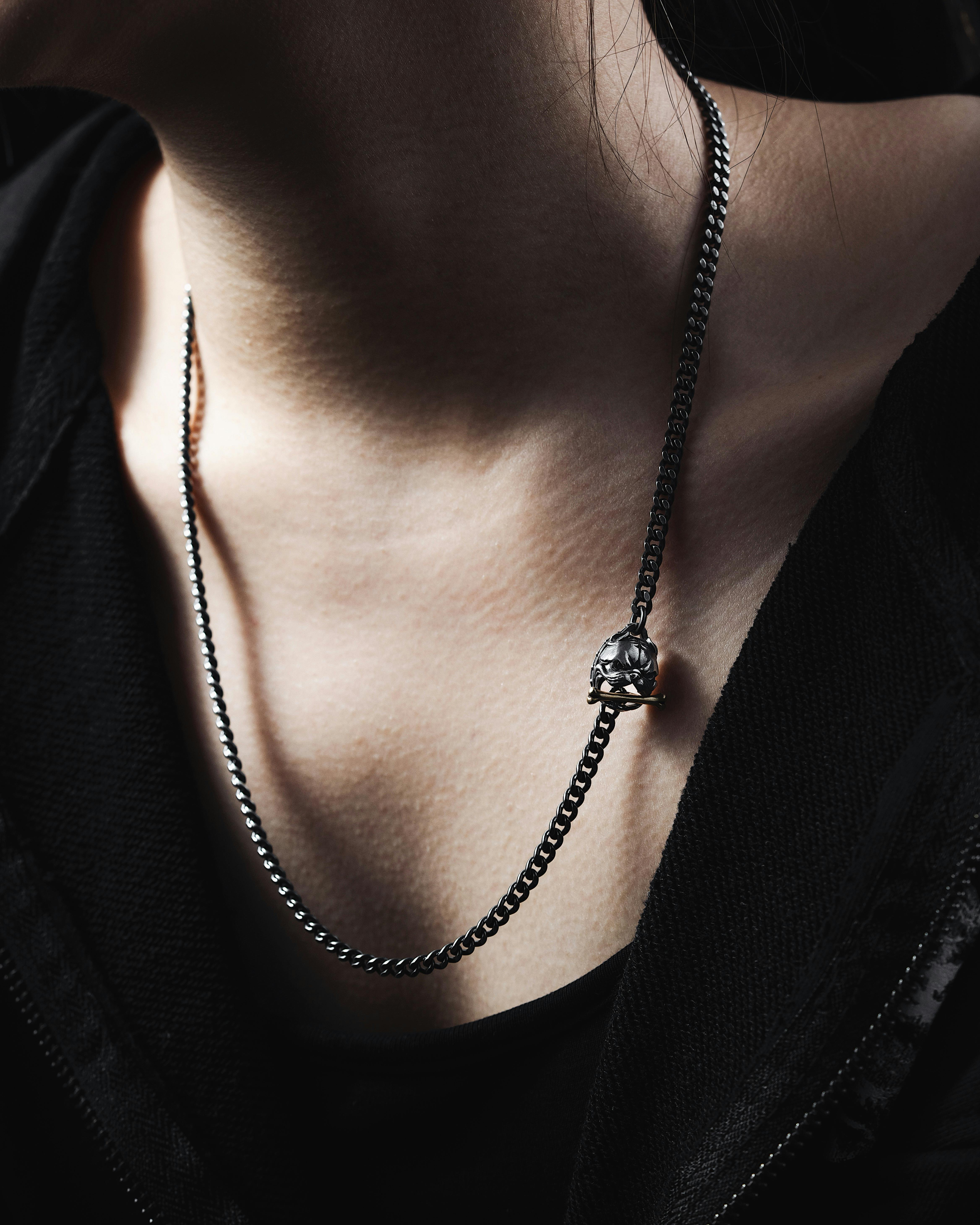 Close-up image showcasing a skull-shaped silver necklace on a person's neck, highlighting the jewelry detail.