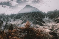 在明亮多云的天空下，雄伟的山峰展现出一片戏剧性的冬季景观