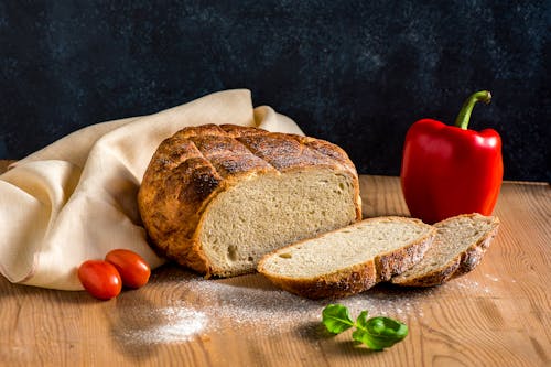 Fresh Sourdough Bread, Pepper, Tomatoes and Basil on a Wooden Table 