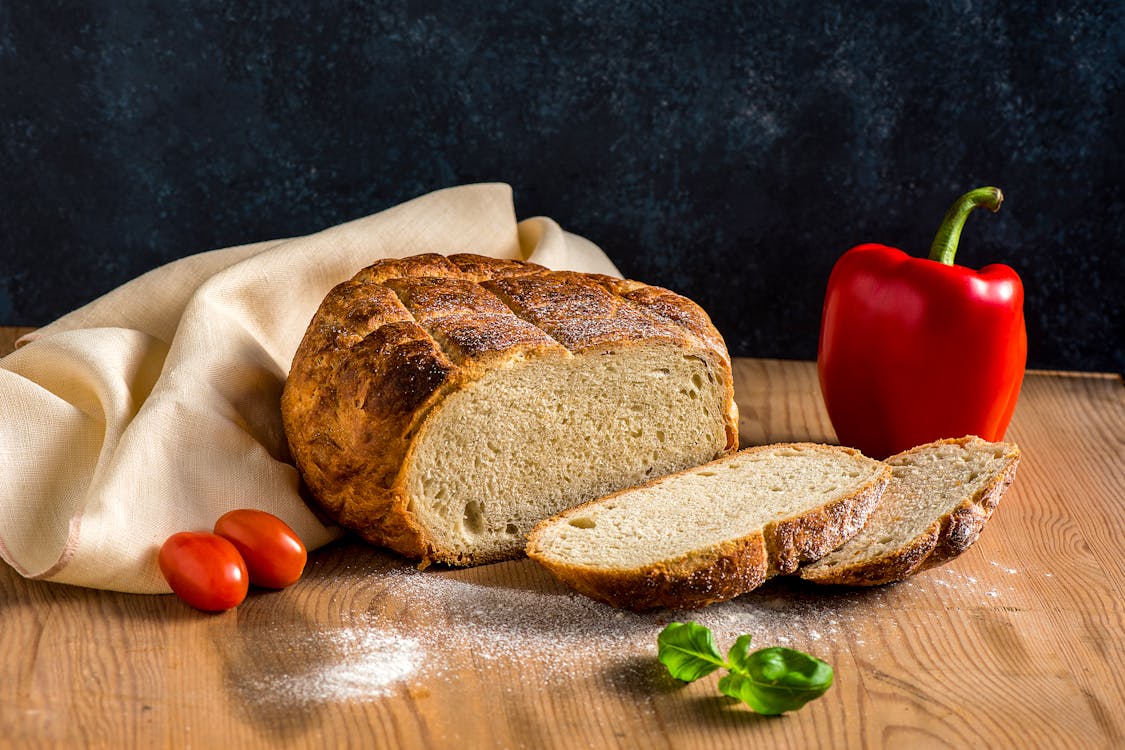 Fresh Sourdough Bread, Pepper, Tomatoes and Basil on a Wooden Table 