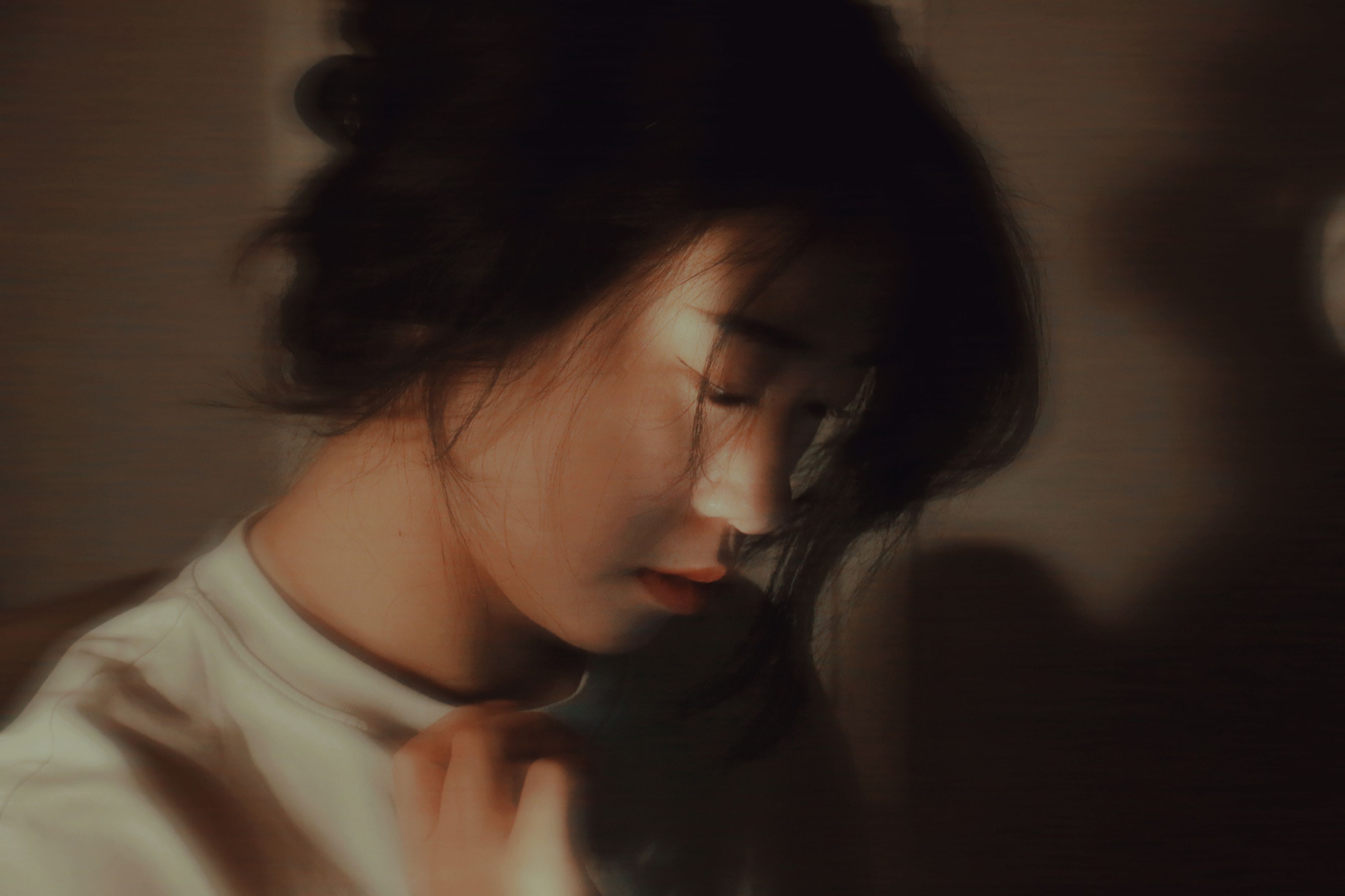 Soft focus portrait of a woman with eyes closed, bathed in warm light.