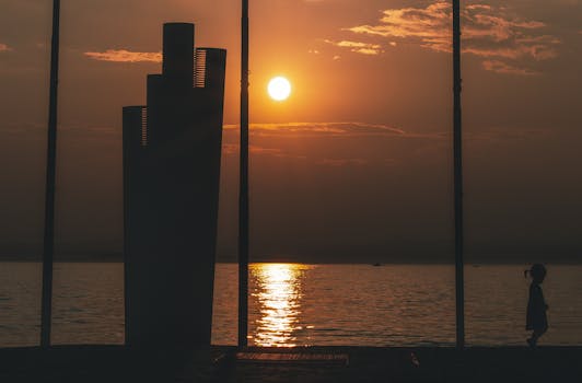 Serene sunset scene with a solitary silhouette against a tranquil sea horizon. Perfect for peaceful themes.