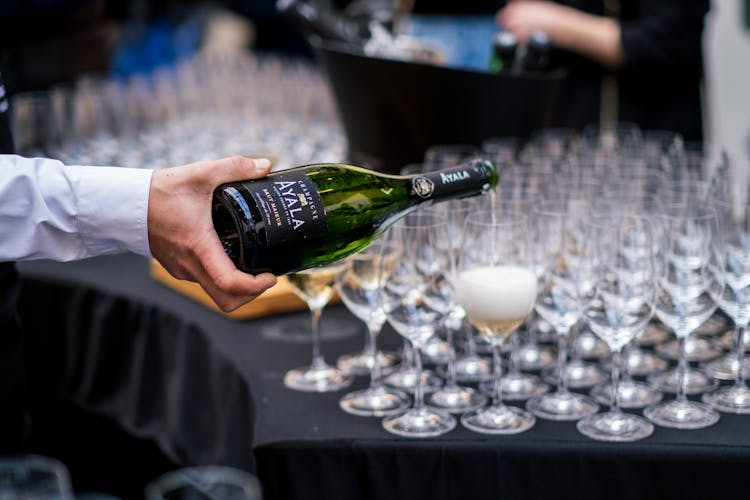 A Person Pouring Champagne Into Glasses