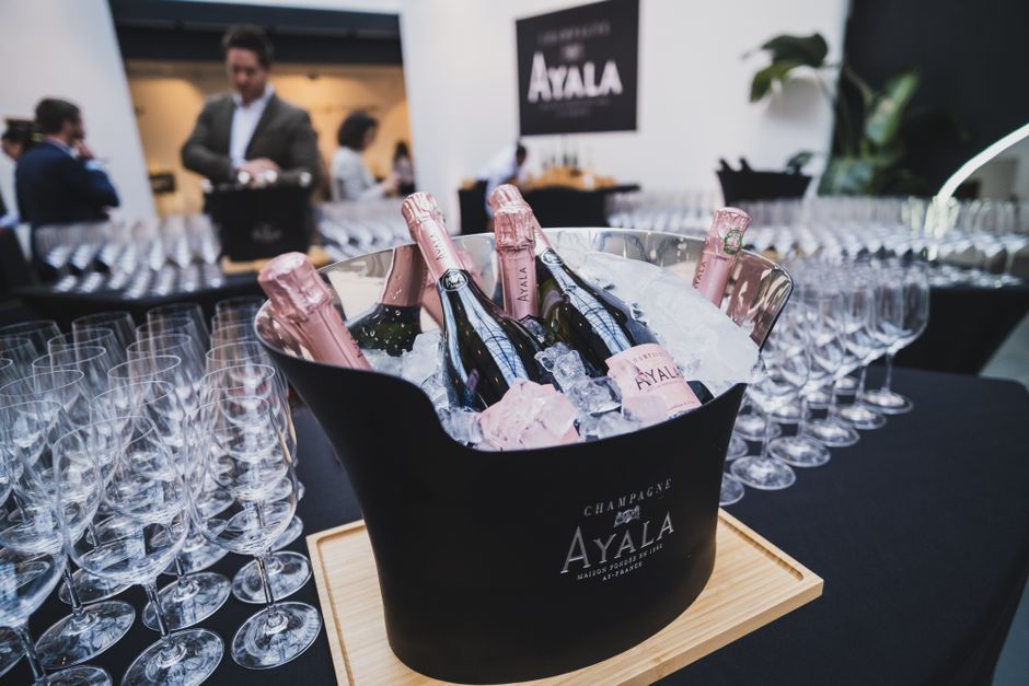 An elegant arrangement of Ayala champagne bottles in an ice bucket surrounded by glasses, perfect for a lavish celebration.