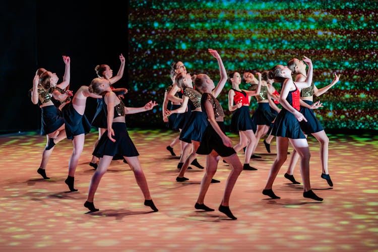 A Group Of Young Girls In Costumes Dancing On A Stage 