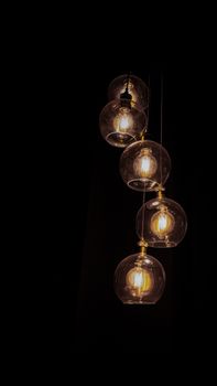 Elegant arrangement of illuminated glass pendant lights with a minimalistic design on a dark background.