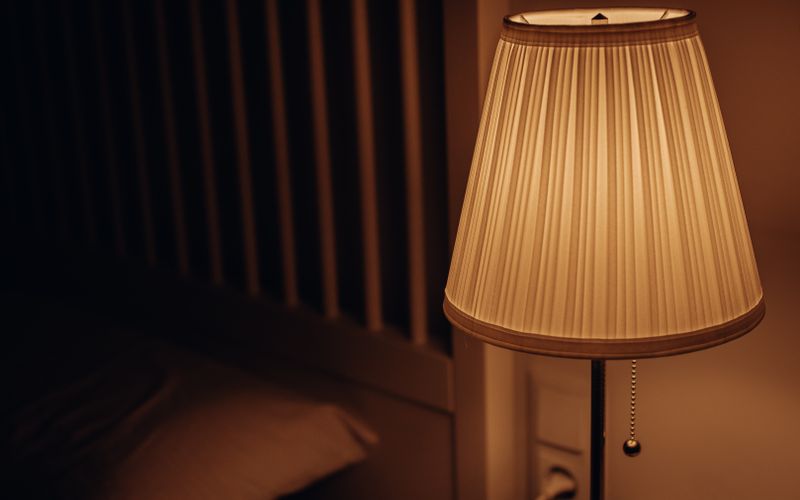 A dimly lit bedside lamp creating a warm and cozy atmosphere in a bedroom setting.