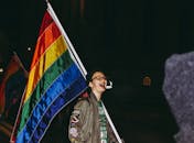 一个人在夜间活动中挥舞彩色的骄傲旗，庆祝喜悦与自由