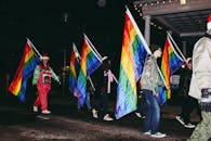 人们在夜间举行色彩缤纷的骄傲游行，举着彩虹旗，表达喜悦