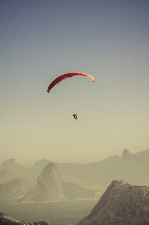 Free Person in Parachute Gliding Above Mountains Stock Photo
