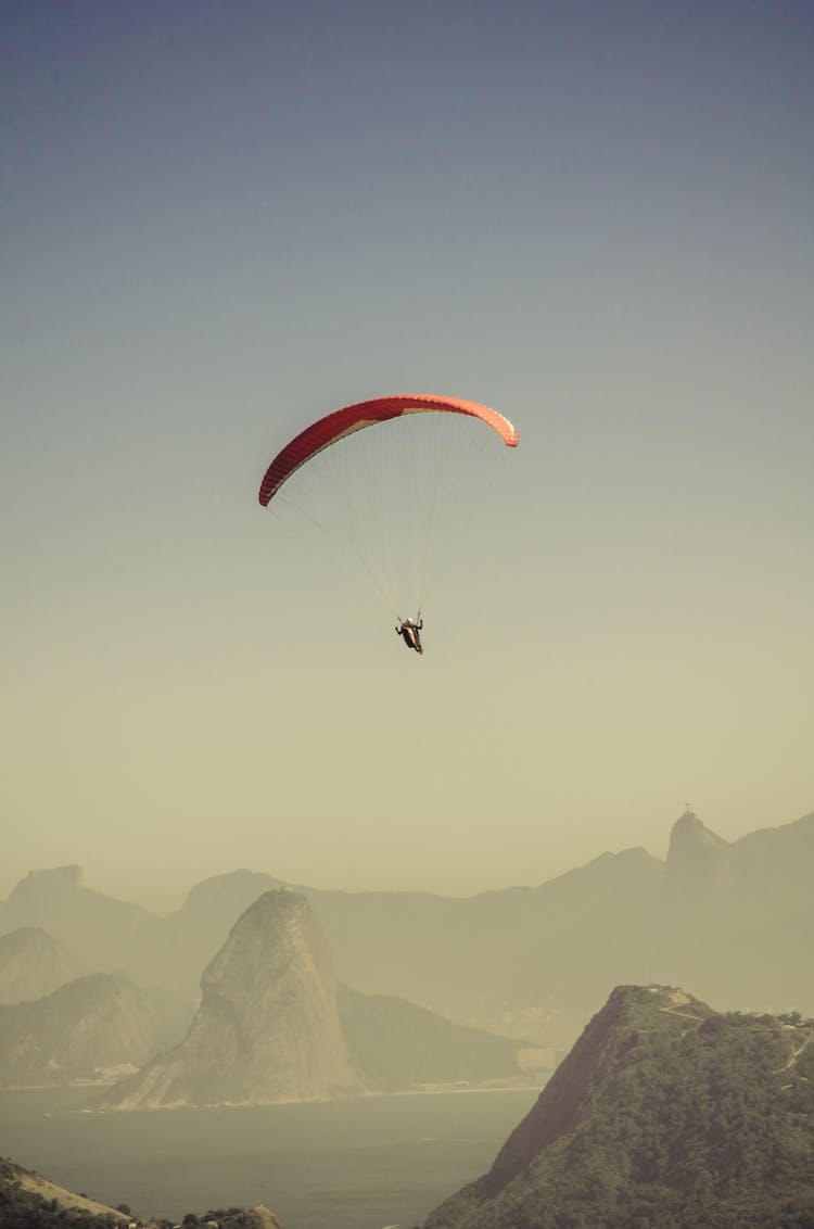 Person In Parachute Gliding Above Mountains