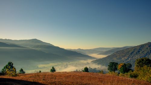 Free Breathtaking sunrise view of misty valleys in Chaukhutiya, India, with lush hills and a peaceful atmosphere. Stock Photo