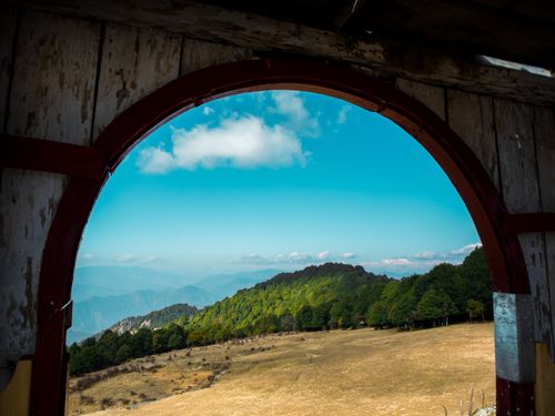 Free Explore the lush mountain landscape of Dwarahat, India through a rustic wooden arch. Stock Photo