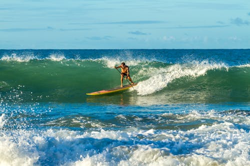 Человек гребет на доске весла с океанскими волнами