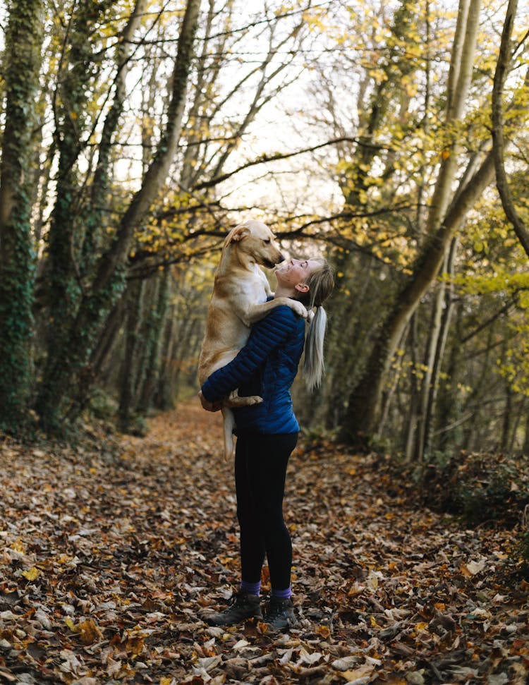 Woman Carrying Dog Outdoors