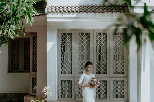 Bride Holding a Bouquet and Standing in front of a Building 