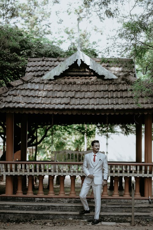 Groom in a Light Suit Posing in a Park 