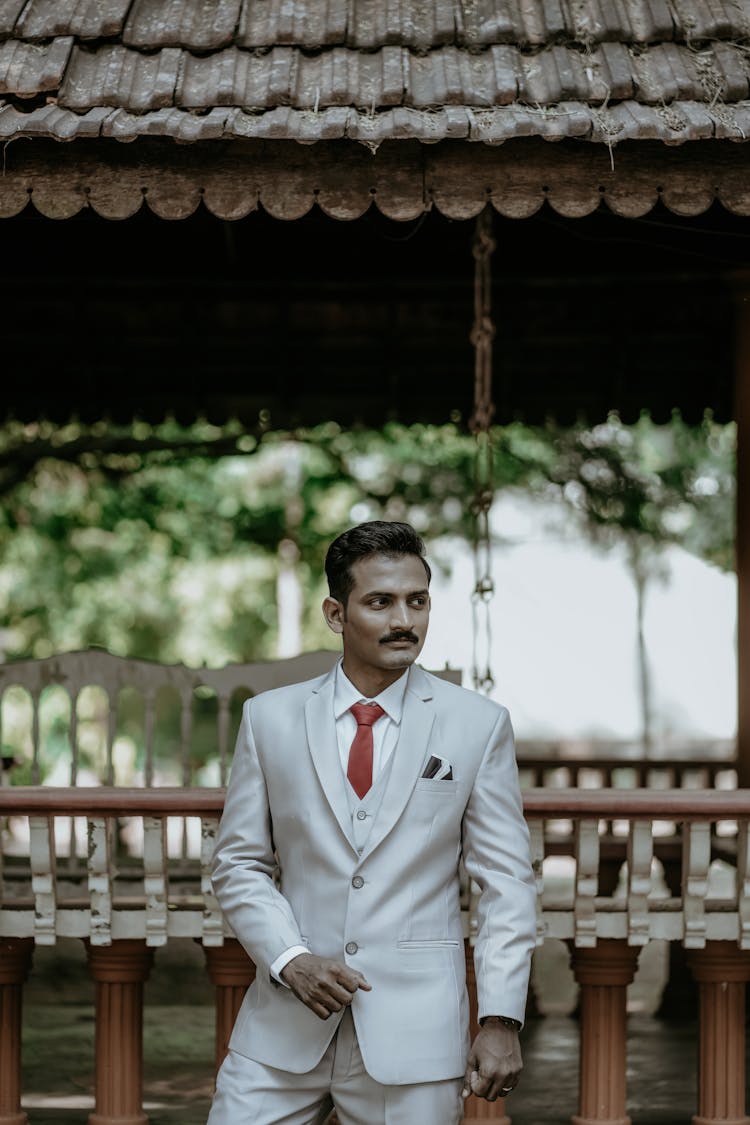 Man In A Suit Standing By A Wooden Bridge