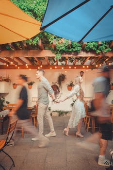 Couple walking hand in hand in colorful outdoor cafe with blurred motion people passing by.
