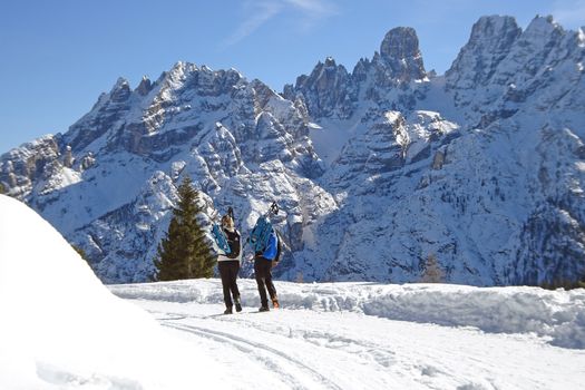 Two people hiking in snowy winter landscape of the Dolomites, Cortina d'Ampezzo, Italy.