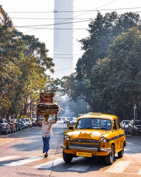 A bustling city street with a man carrying goods and a classic yellow taxi.