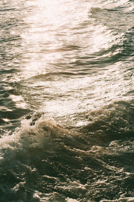 A mesmerizing view of ocean waves reflecting sunlight during twilight, creating a serene and calming atmosphere.