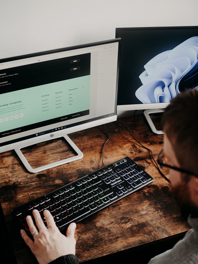 Man Sitting At Desk Working On Computers 