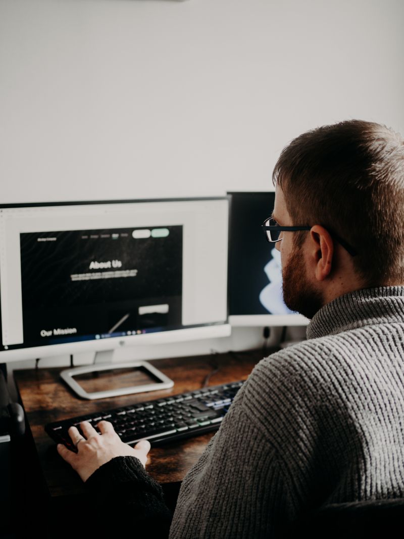 Designer planning website design strategy on dual monitors